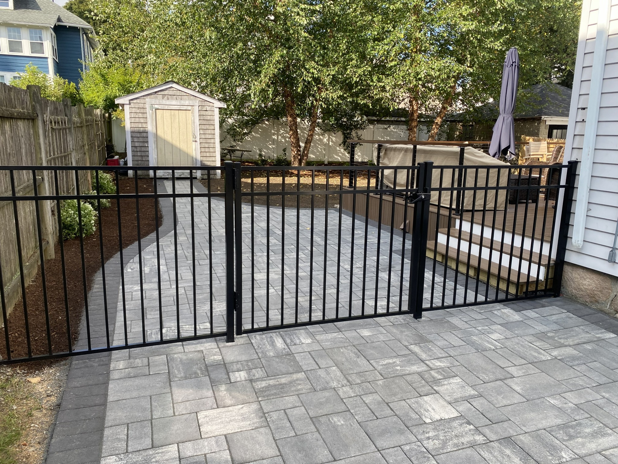 Black aluminum fence and gate beside a paved patio