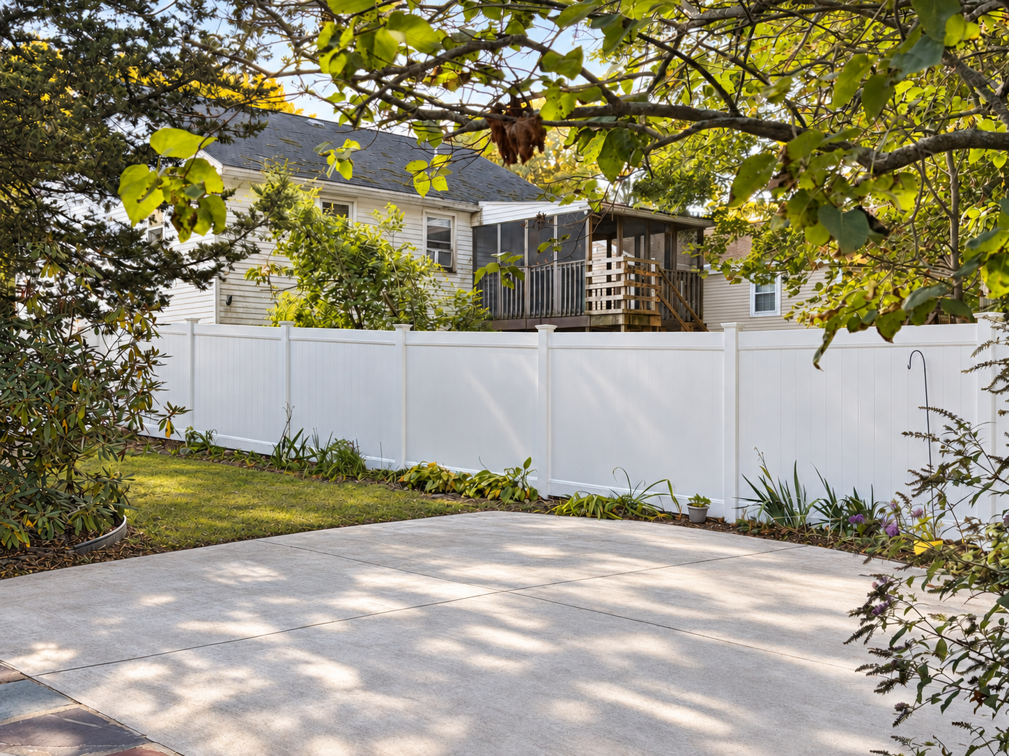 White vinyl privacy fence enclosing a landscaped backyard and patio